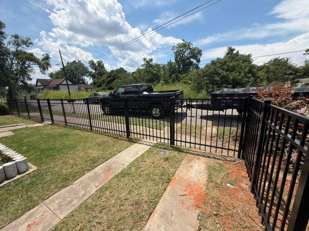 Completed black aluminum fence and walk gate installed around a residential yard