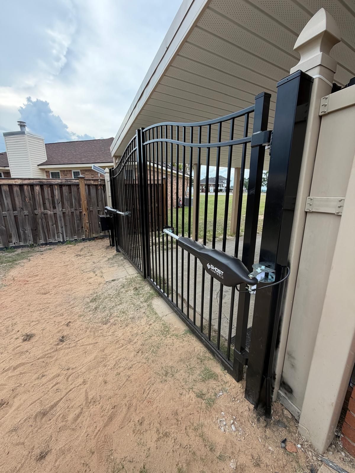 Completed CAMINTEL installation of two automatic gate opener arms on a decorative black driveway gate