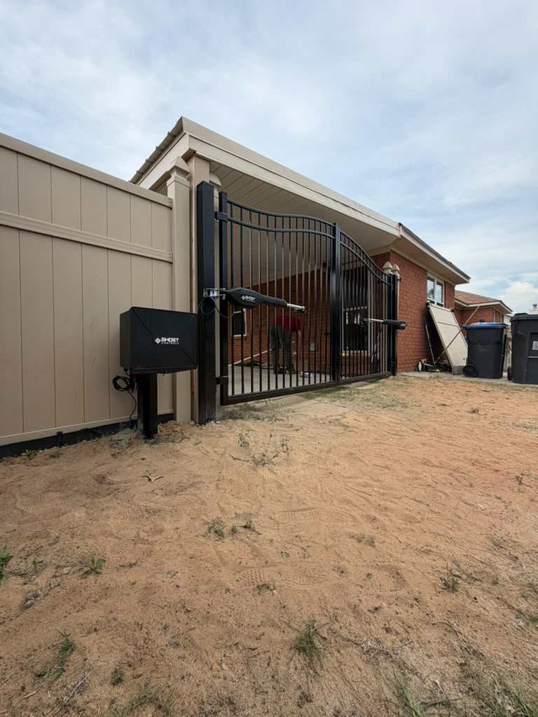 Completed dual automatic gate opener installation on a black metal residential gate