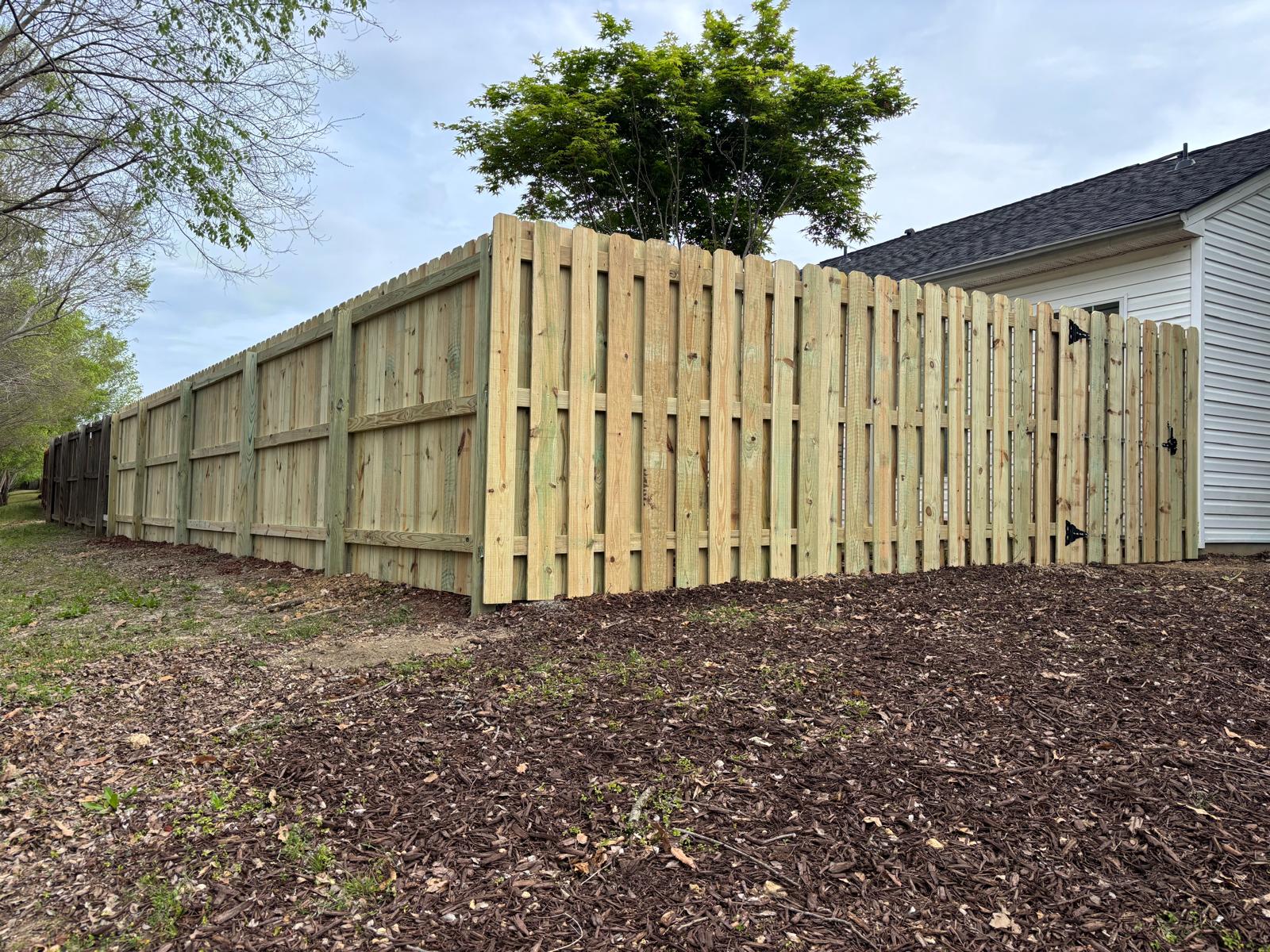Completed wood privacy fence wrapping around a residential yard corner