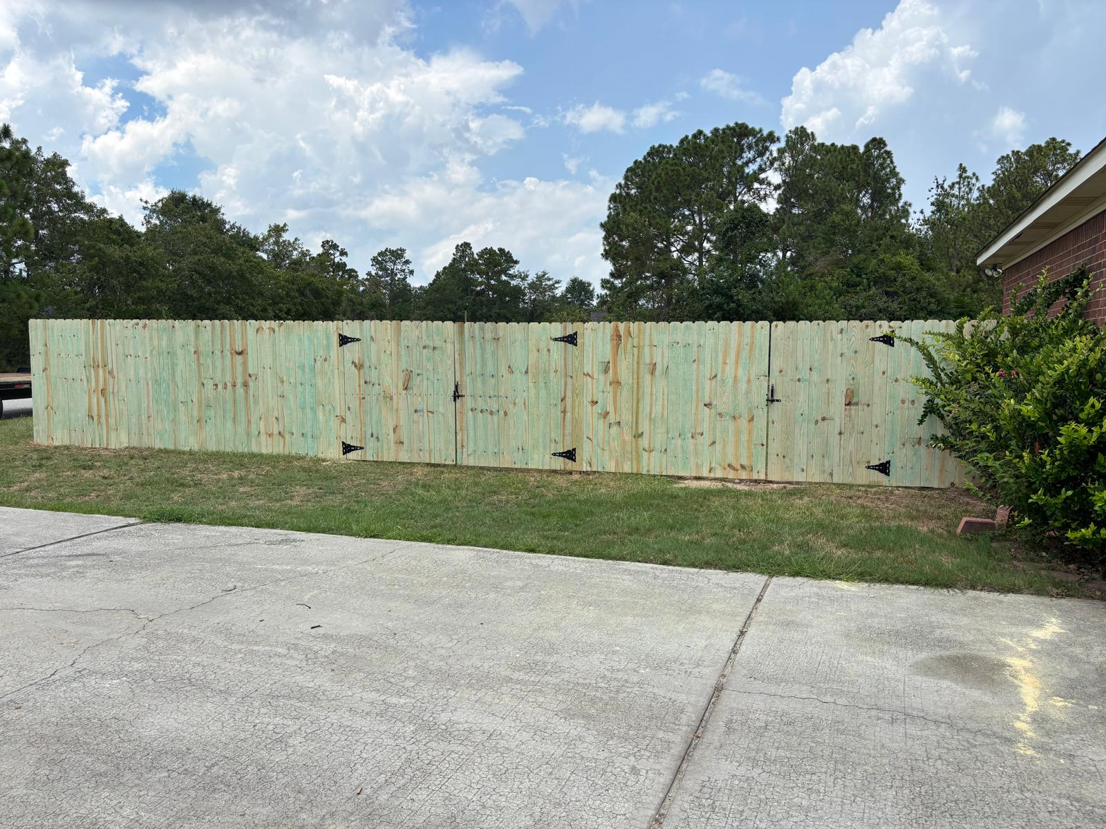 Completed wood privacy fence with multiple driveway gates