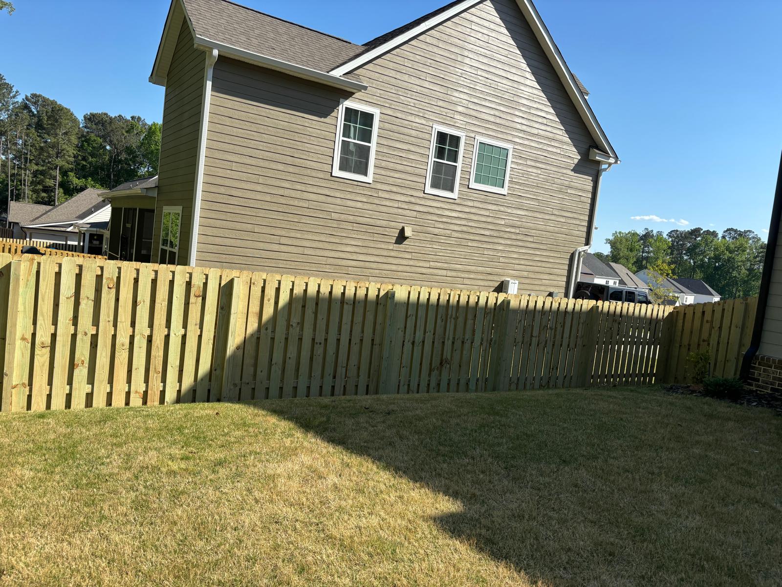 Completed shadowbox-style wood fence beside a residential home