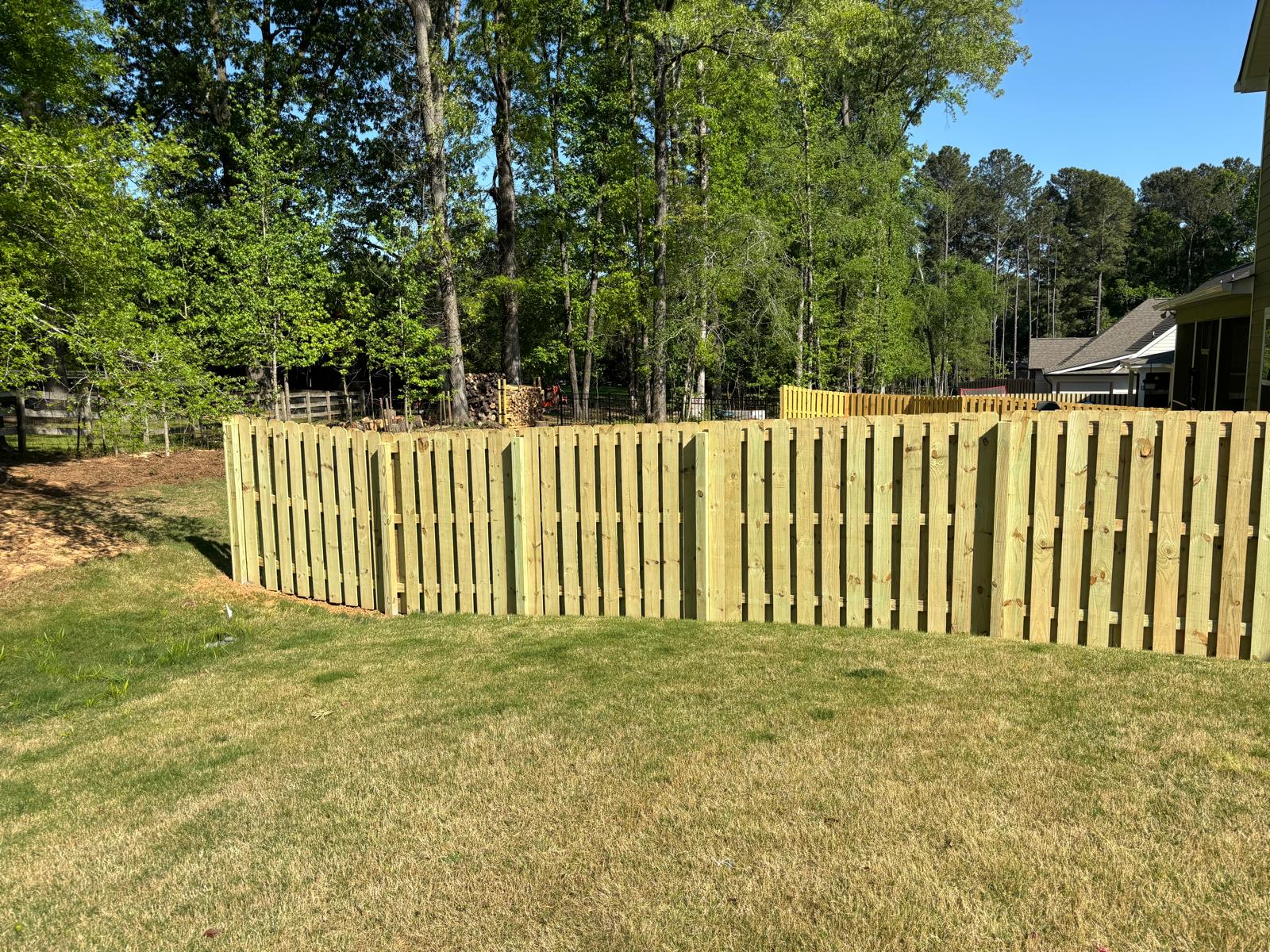 Completed wood shadowbox fence across a residential backyard